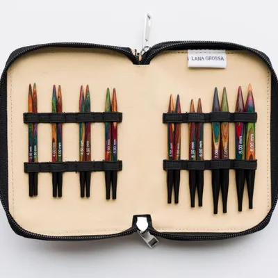 An open knitting needle case with various sizes of knitting needles arranged inside.
