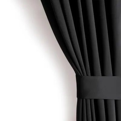 A black curtain is shown draped against a white wall, held by a fabric band.