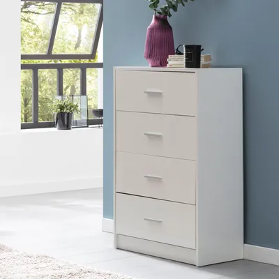 A white chest of drawers with four drawers is shown in a room with a blue wall and a window with greenery outside.