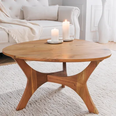 A wooden coffee table with two candles on it, placed in a living room setting with a sofa in the background.