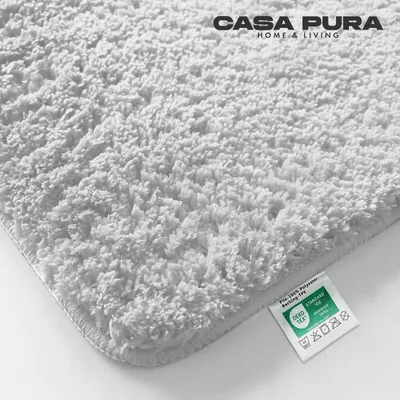 A close-up, angled view of a fluffy white rug with a small label attached to the corner.