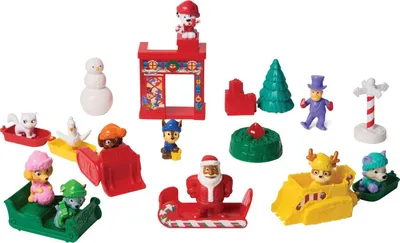 A collection of small Christmas-themed toys, likely from an advent calendar, featuring Paw Patrol characters and festive elements.