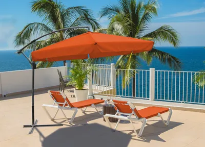 A patio scene with lounge chairs and an umbrella overlooking the ocean.