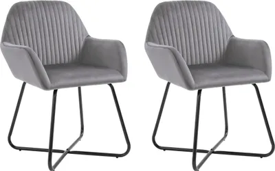 Two gray velvet dining chairs with black metal legs are shown against a white background.