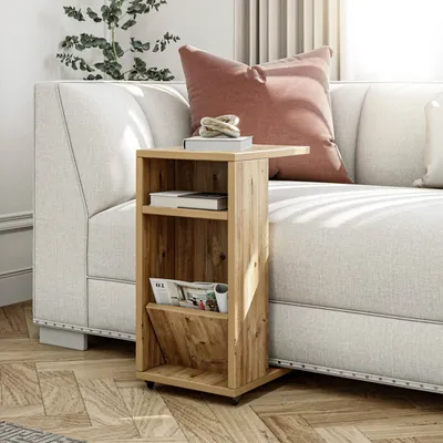 A wooden side table with shelves and a magazine holder is placed next to a sofa in a living room.