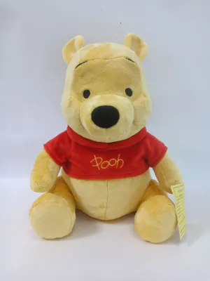 A plush toy of Winnie the Pooh sitting down, wearing a red shirt.