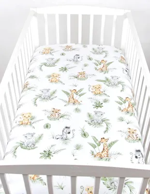 A crib with a fitted sheet featuring a jungle animal print.