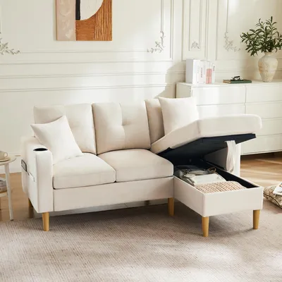 A beige sectional sofa with its storage ottoman open, revealing stored items. The sofa is in a well-lit room with decorative elements in the background.