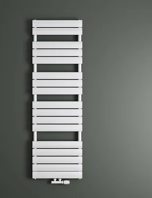 A white radiator is mounted on a gray wall.