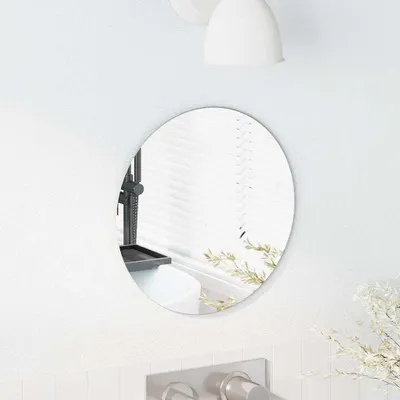 A round mirror mounted on a white wall above a sink.