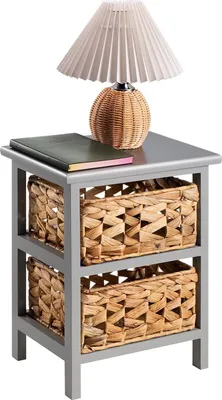 A small gray nightstand with two woven baskets and a lamp on top.