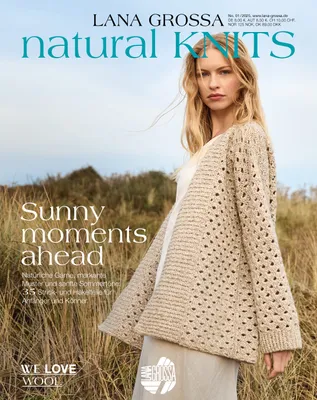 A woman wearing a knitted cardigan stands in a field of tall grass.