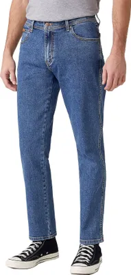 A person wearing blue jeans and black sneakers, shown from the waist down, against a white background.