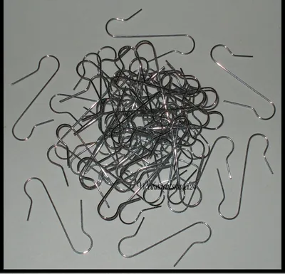 A pile of silver metal ornament hooks on a light gray background.
