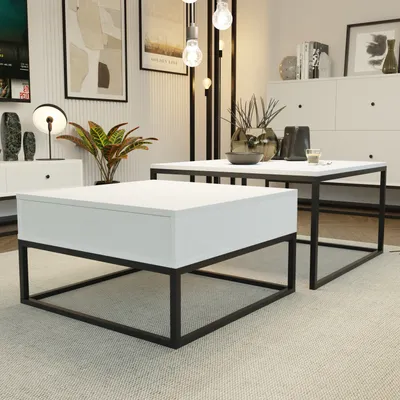 A modern living room setting with two white coffee tables with black metal frames, one larger and one smaller, placed on a light-colored rug. Decorative items and artwork are visible in the background.