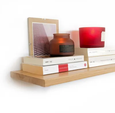 A wooden shelf with books, a candle, and a framed picture.