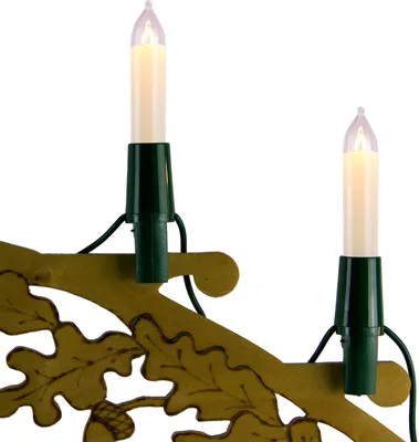 Close-up of two candle-shaped lights attached to a decorative golden branch with oak leaf motifs.