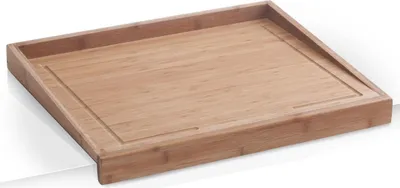 A bamboo cutting board with a juice groove, resting on a white surface.