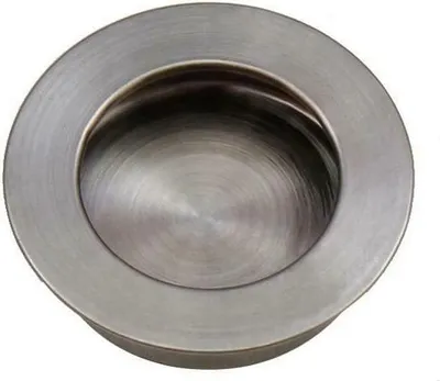 A close-up, top-down view of a circular, recessed drawer pull or handle made of brushed metal.