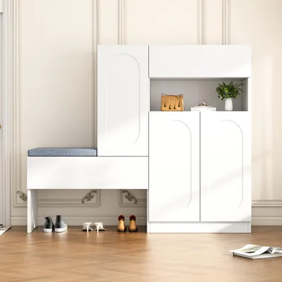 A white shoe cabinet with a bench and cushion, placed in a room with light-colored walls and wooden flooring.