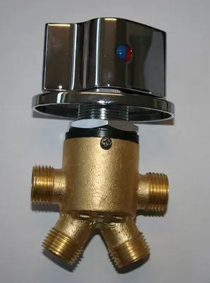 A close-up studio shot of a brass and chrome water mixing valve with a diverter.