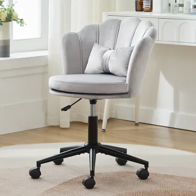 A gray velvet office chair with a scalloped back and a small decorative pillow is shown in a well-lit room.