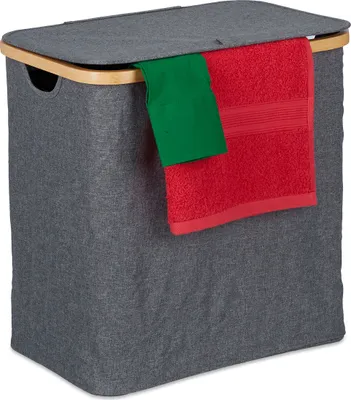 A grey fabric laundry basket with a wooden rim and a lid, with a red and green towel draped over the edge.