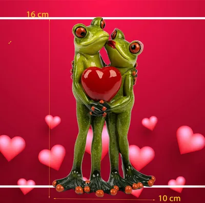 A decorative sculpture of two frogs hugging a heart, set against a red background with heart shapes.