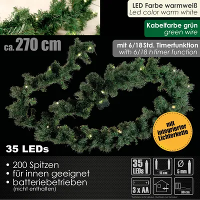 A dark background with a green Christmas garland illuminated by warm white LEDs.