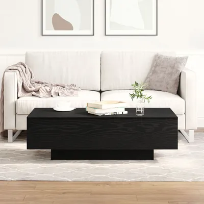 A black coffee table in front of a white sofa in a living room.
