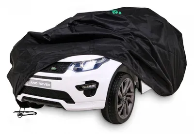 A white Land Rover toy car is partially covered by a black car cover.