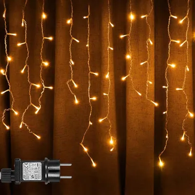 A string of warm white LED icicle lights hanging against a brown curtain.