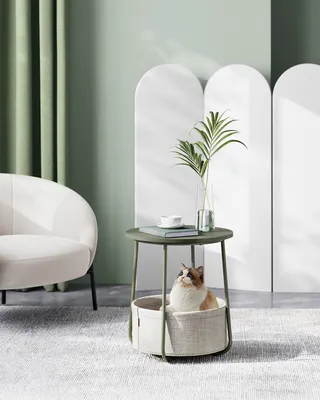 A cat sits in a pet bed integrated into a side table in a modern living room.