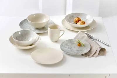 A collection of ceramic tableware, including plates, bowls, and a mug, arranged on a white surface.