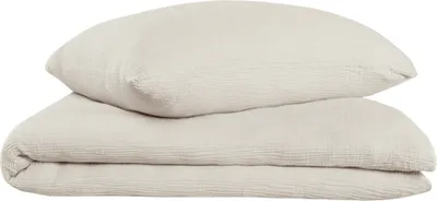 A folded duvet and a pillow, both in a light taupe color, are stacked on a white background.