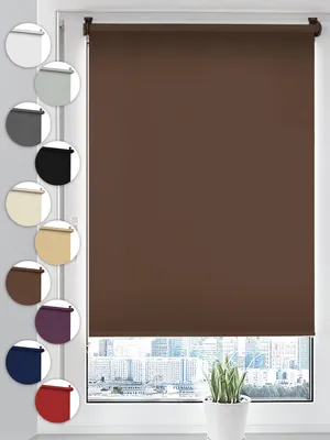 A brown roller blind is shown in the center of the image, with a selection of other color swatches arranged vertically on the left side. The background shows a blurred cityscape through a window.