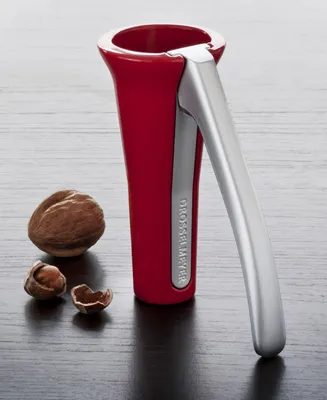 A red and silver nutcracker with nuts on a dark wooden surface.