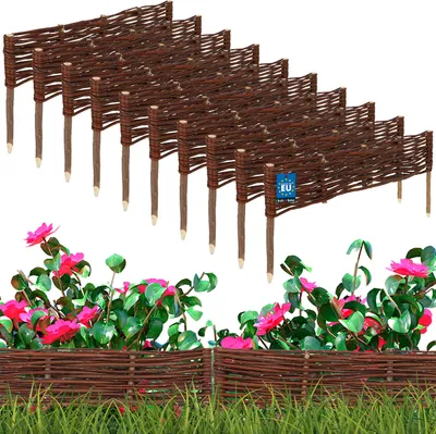 A set of brown wicker garden fences with pointed stakes, displayed in front of pink flowers and green grass.