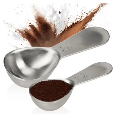Two stainless steel measuring spoons, one filled with brown powder, against a white background with a brown powder explosion effect.