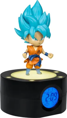 A Goku figurine is displayed on top of a black alarm clock with a digital display.