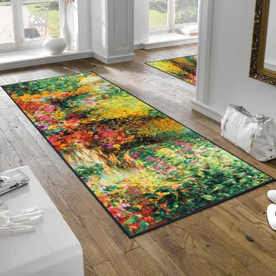 A long runner rug with a floral garden print is laid on a wooden floor in a hallway, next to a white console table and a large white handbag.