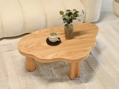 A wooden coffee table with a vase and a cup on it, placed on a rug next to a sofa.