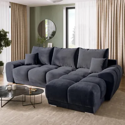 A modern living room with a large sectional sofa, coffee table, and curtains.