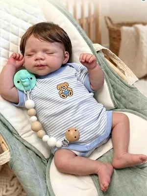 Imagen del producto de Muñeco de silicona de cuerpo completo, con 48 cm de altura, ojos cerrados, cabello implantado y pestañas permanentes; body a rayas con estampado de osito Pascale; figura de muñeco realista. Niño de silicona de cuerpo completo