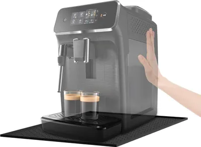 A hand is shown interacting with a coffee machine, with two cups of coffee beneath the dispenser.