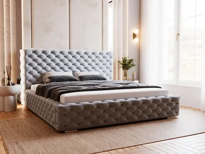 A tufted upholstered bed with pillows and a blanket in a well-lit bedroom setting.