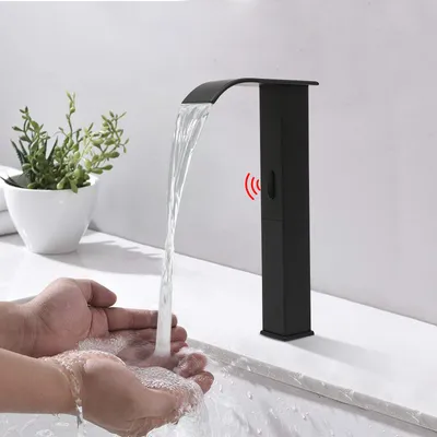 Hands being washed under a black waterfall faucet with a red sensor indicator.