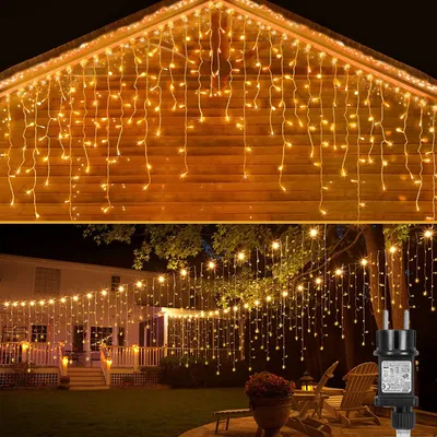 Outdoor scene at night with houses and trees decorated with string lights.