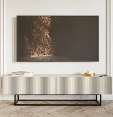 A TV lowboard with a ribbed front and a black metal frame, placed in a room setting with a TV mounted on the wall above it.
