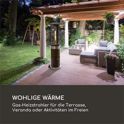 A gas patio heater is shown on a wooden deck at dusk, with outdoor furniture and a swing set in the background.